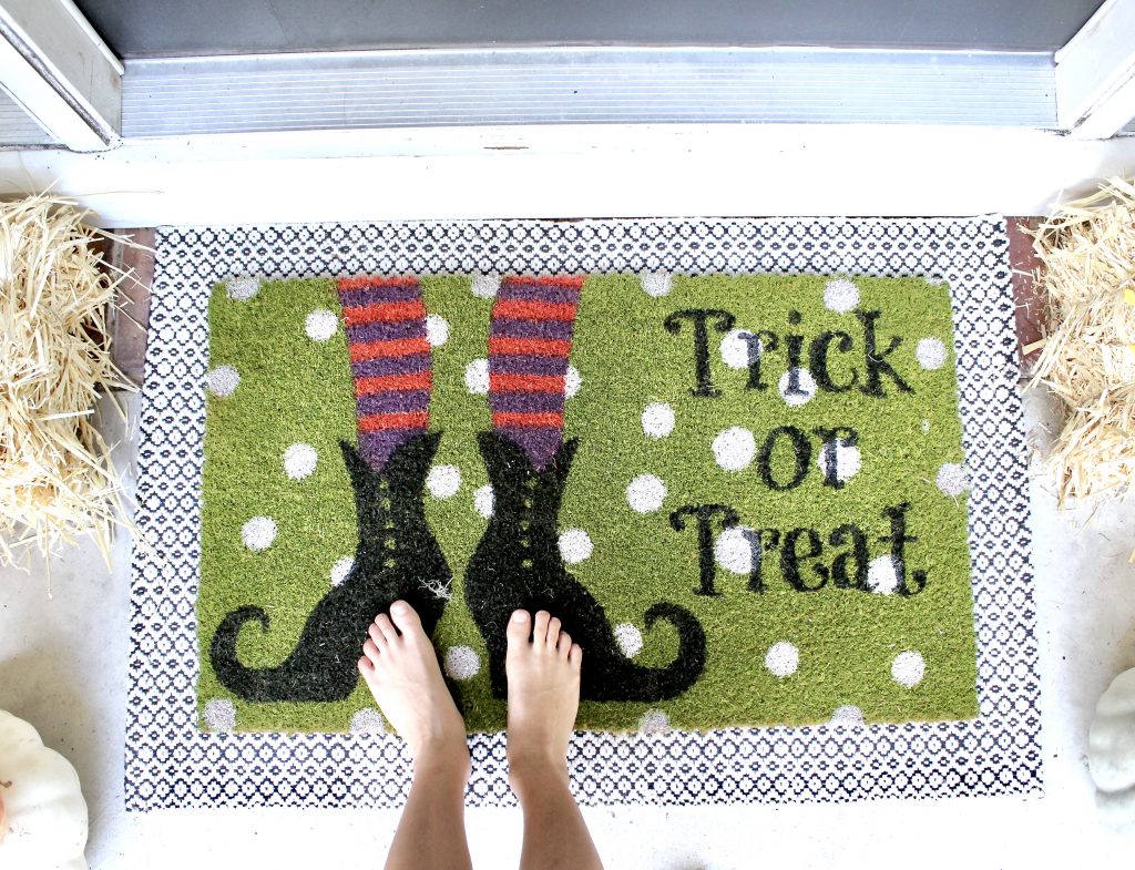 halloween doormat layered over black and white rug
