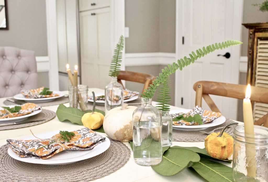 Thanksgiving tablescape with ferns pumpkins and candles