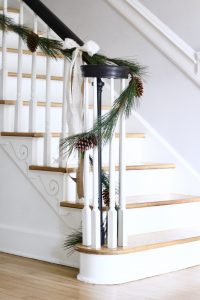 Neutral Christmas Decor - long leaf pine garland on black stairway railing with cream and burlap ribbon bow | www.ourhammockhouse.com 