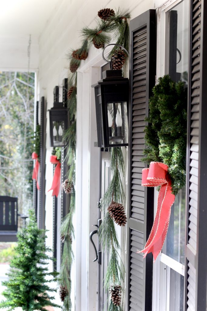 White modern farmhouse with black shutters and wreaths with red bows on the windows | #modernfarmhouse #frontporch #Christmasdecor #wreath