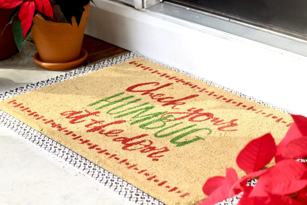 Christmas doormat layered over rug with red poinsettias |#frontporch #frontdoor #doormat #poinsettia 