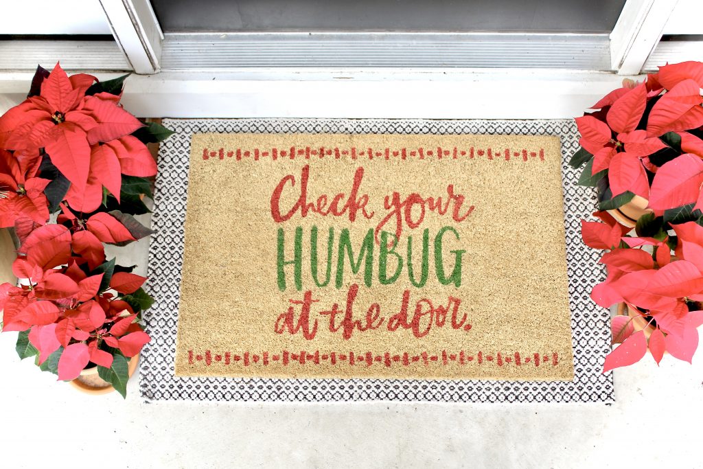 Christmas doormat layered over rug with red poinsettias |#frontporch #frontdoor #doormat #poinsettia 