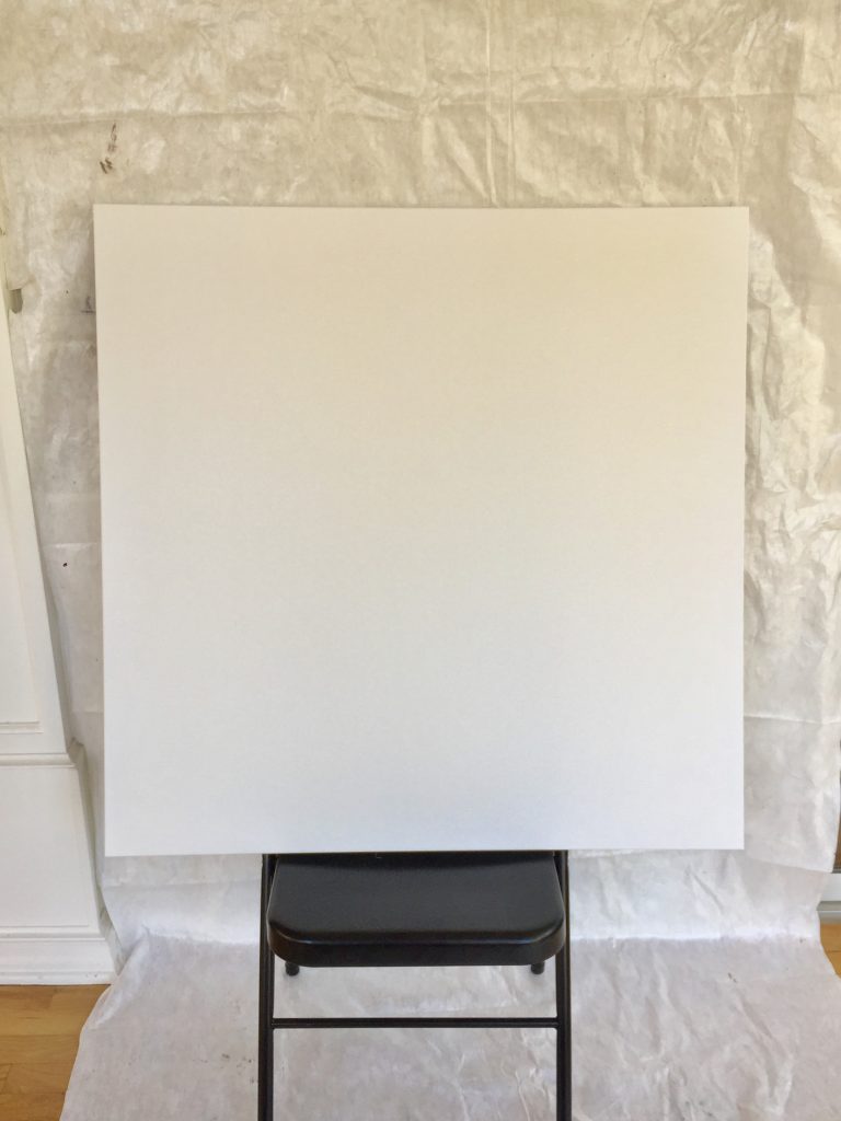 Drop cloth taped to wall with canvas resting on folding chair 