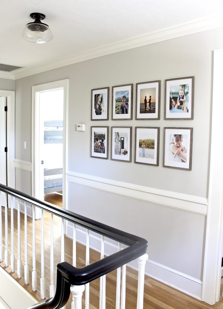 Tips and layout ideas for hanging a minimalist, grid-style gallery wall along your staircase or hallway with affordable frames and family photos | www.ourhammockhouse.com | #gallerywall #gridstylegallerywall #blackhandrail #familyphotos 
