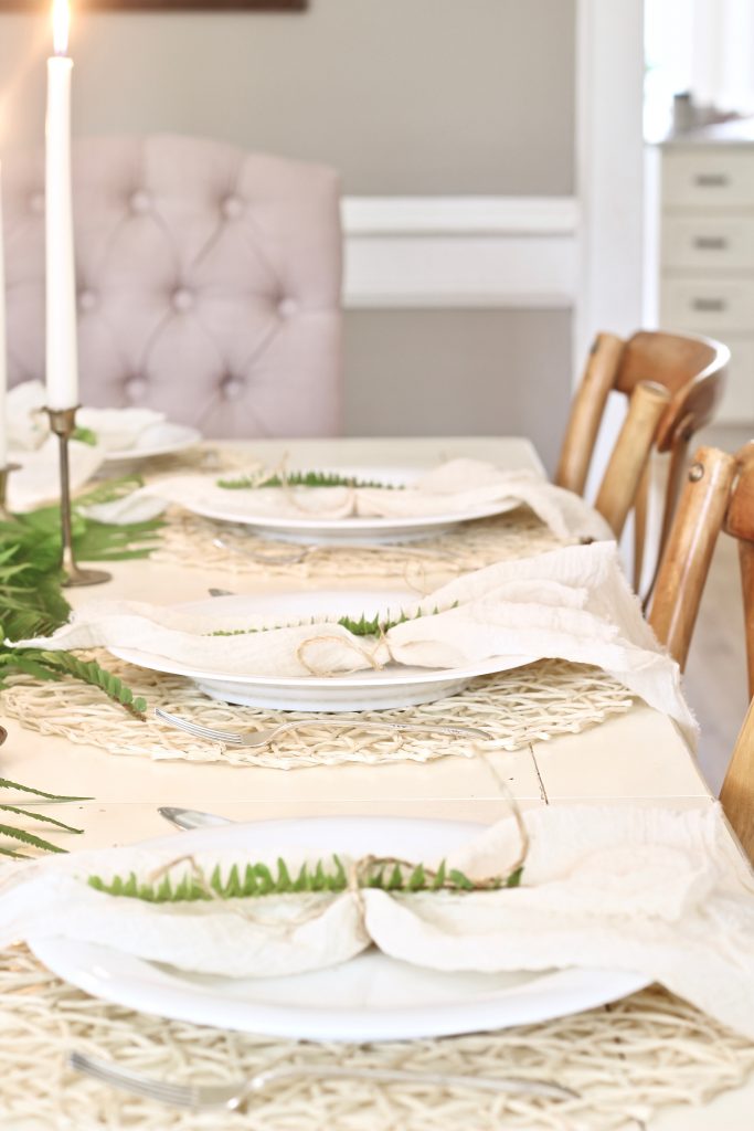 Decorate your dining table for spring or Easter with vintage brass candlesticks, ferns, and gauze napkins tied with twine | www.ourhammockhouse.com | #tablescape #springtable #eastertable #springdecor #easterdecor #gauzenapkin #brasscandlesticks 