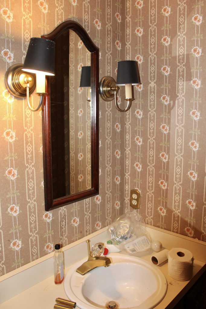Dated 80s powder room with old vanity and yellow brass sconces 