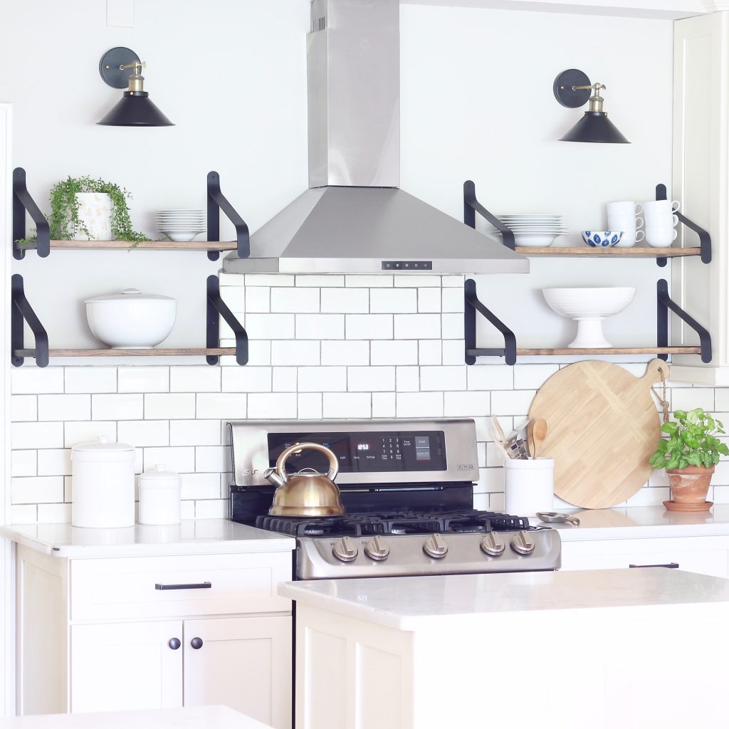 Easily turn hardwired sconces into wireless sconces! See how we installed these black and brass sconces above the open shelves in our white kitchen | www.ourhammockhouse.com | #wirelesssconce #blacksconce #wallsconce #openshelves #whitekitchen