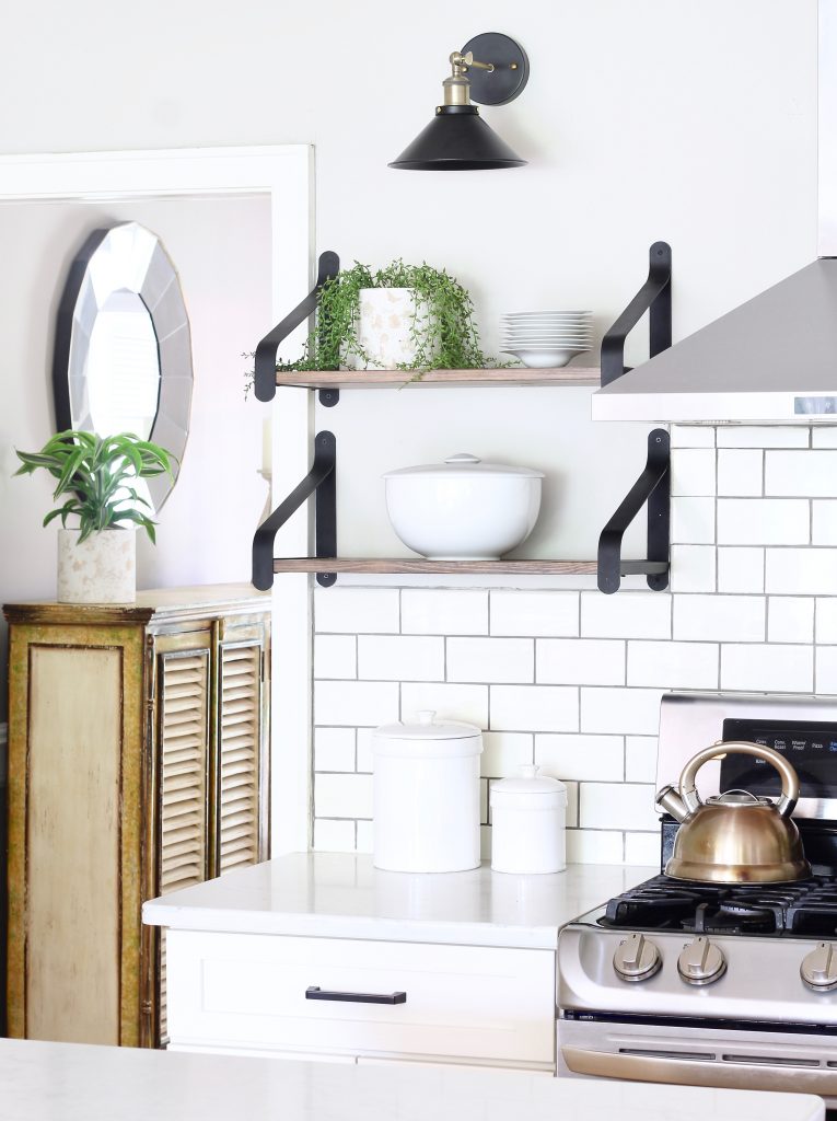 Easily turn hardwired sconces into wireless sconces! See how we installed these black and brass sconces above the open shelves in our white kitchen | www.ourhammockhouse.com | #wirelesssconce #blacksconce #wallsconce #openshelves #whitekitchen